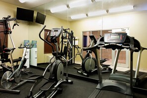 A gym with various exercise equipment including treadmills, stationary bikes, and weight machines.