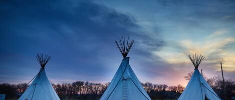 Three tipi-style tents arranged in a row with a clear sky in the background.