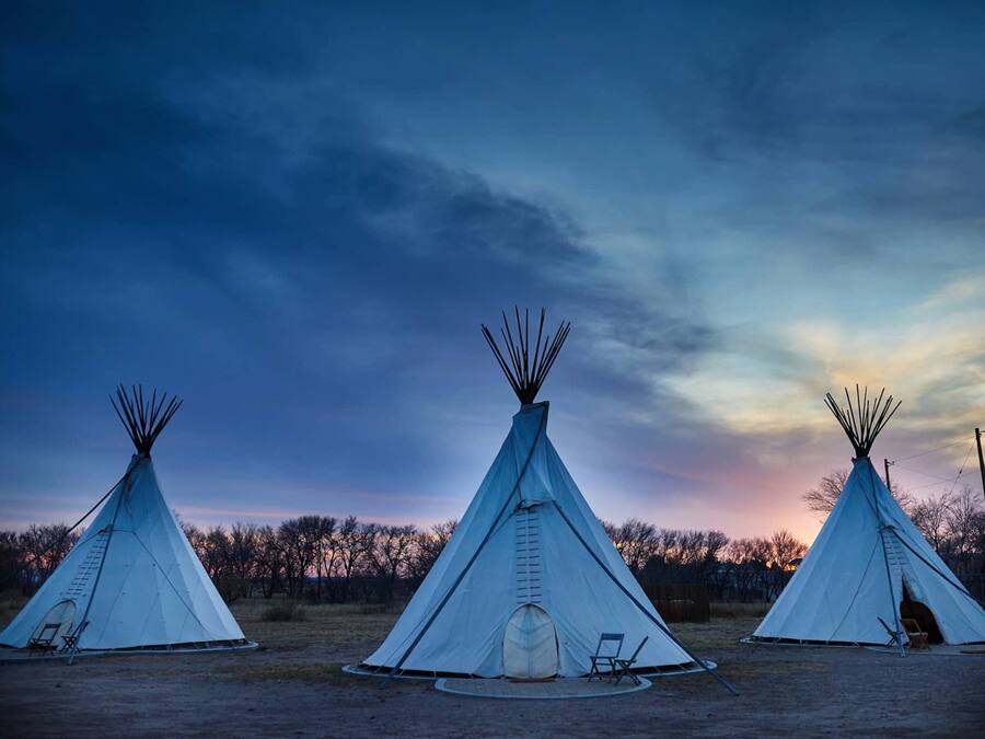 Three tipi-style tents arranged in a row with a clear sky in the background.