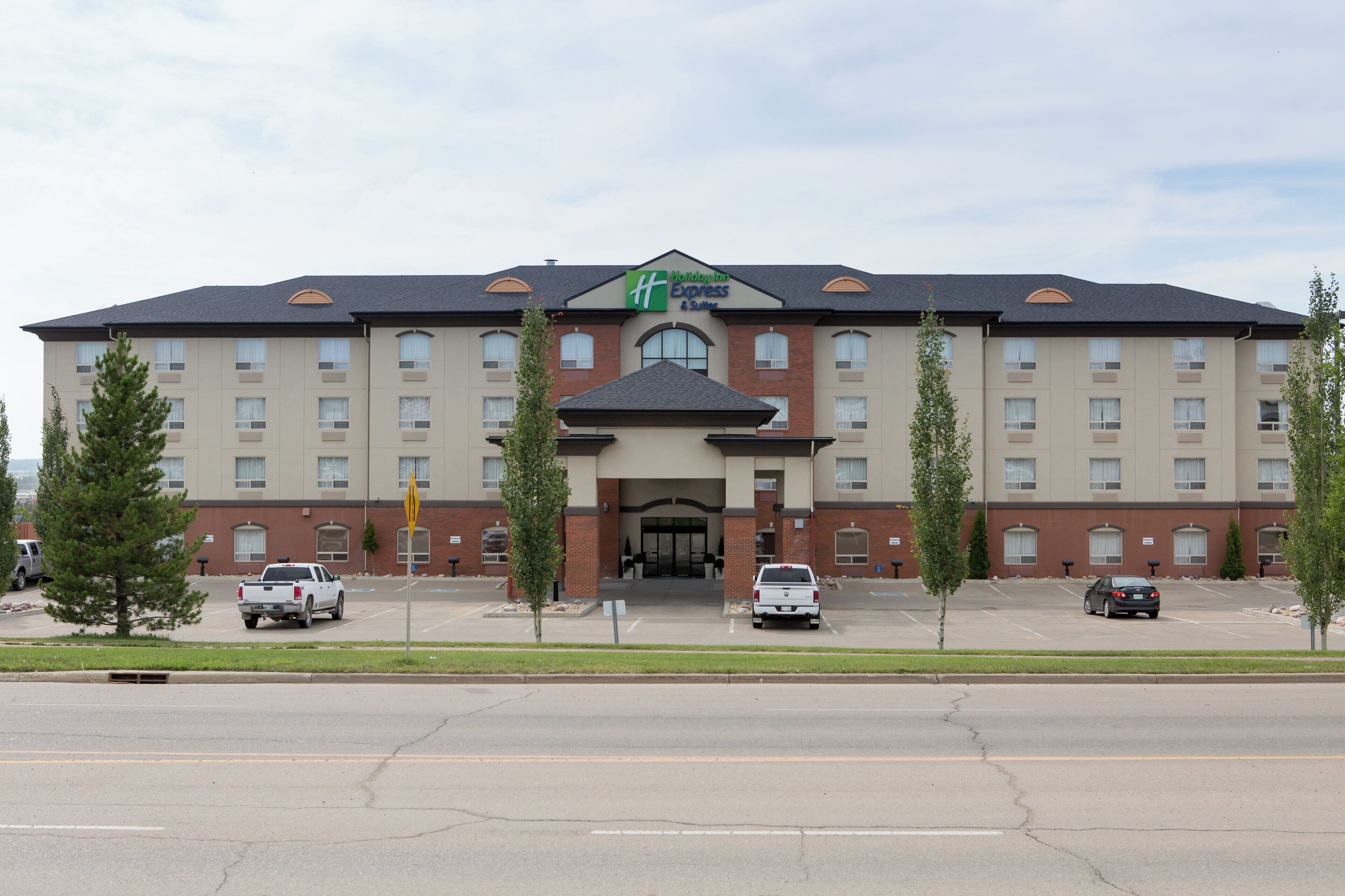 A Holiday Inn Express & Suites hotel with a symmetrical facade, multiple windows, and a central entrance.