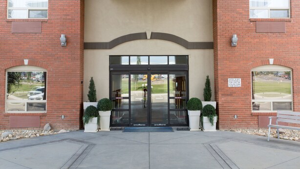 A hotel entrance with a brick facade, large glass doors, and a bench outside. - Holiday Inn Express Hotel & Suites Drayton Valley by IHG (Drayton Valley)