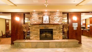 A lobby with a stone fireplace, wooden walls, and a tiled floor. - Holiday Inn Express Hotel & Suites Drayton Valley by IHG (Drayton Valley)