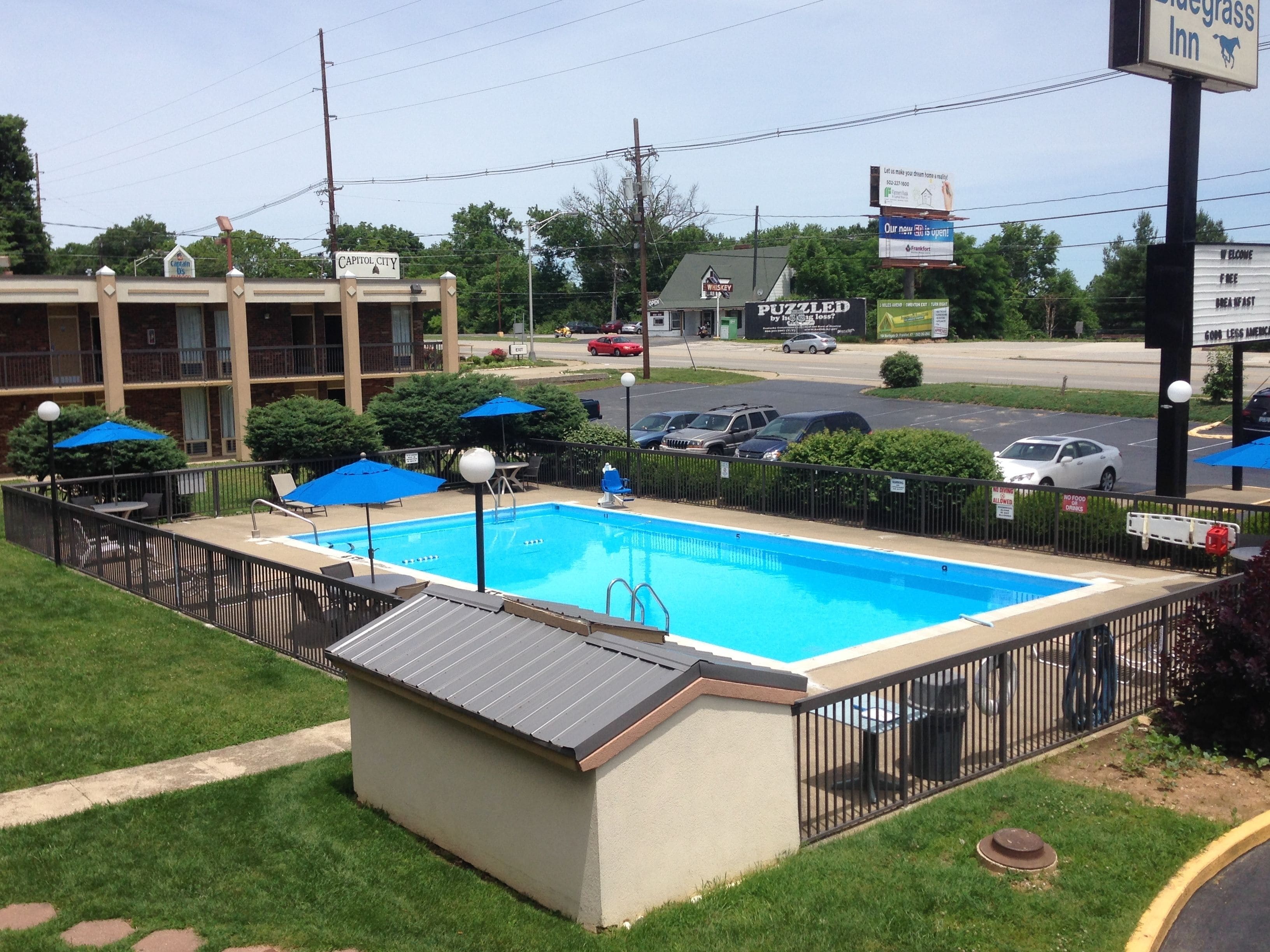 A swimming pool with a fenced deck, surrounded by a building with a sign reading "Capitol City".