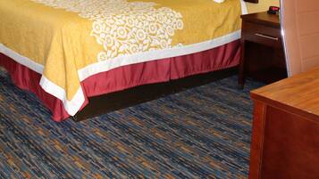 Una habitación de hotel con cama, mesita de noche, lámpara y un cuadro en la pared.