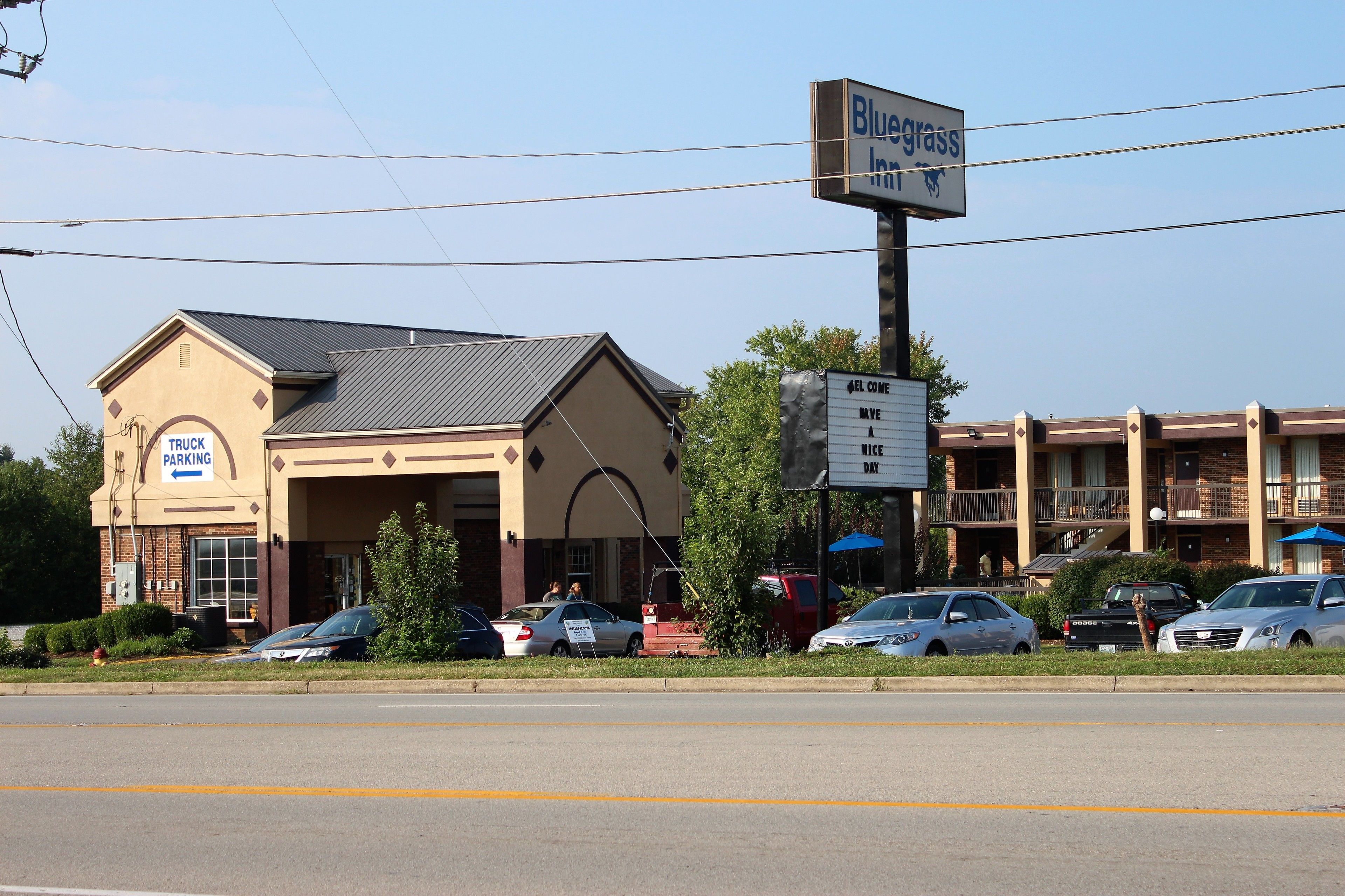 A motel with a 'TRUCK PARKING' sign, a 'Bluegrass Inn' sign, and a '4EL COVE' sign.