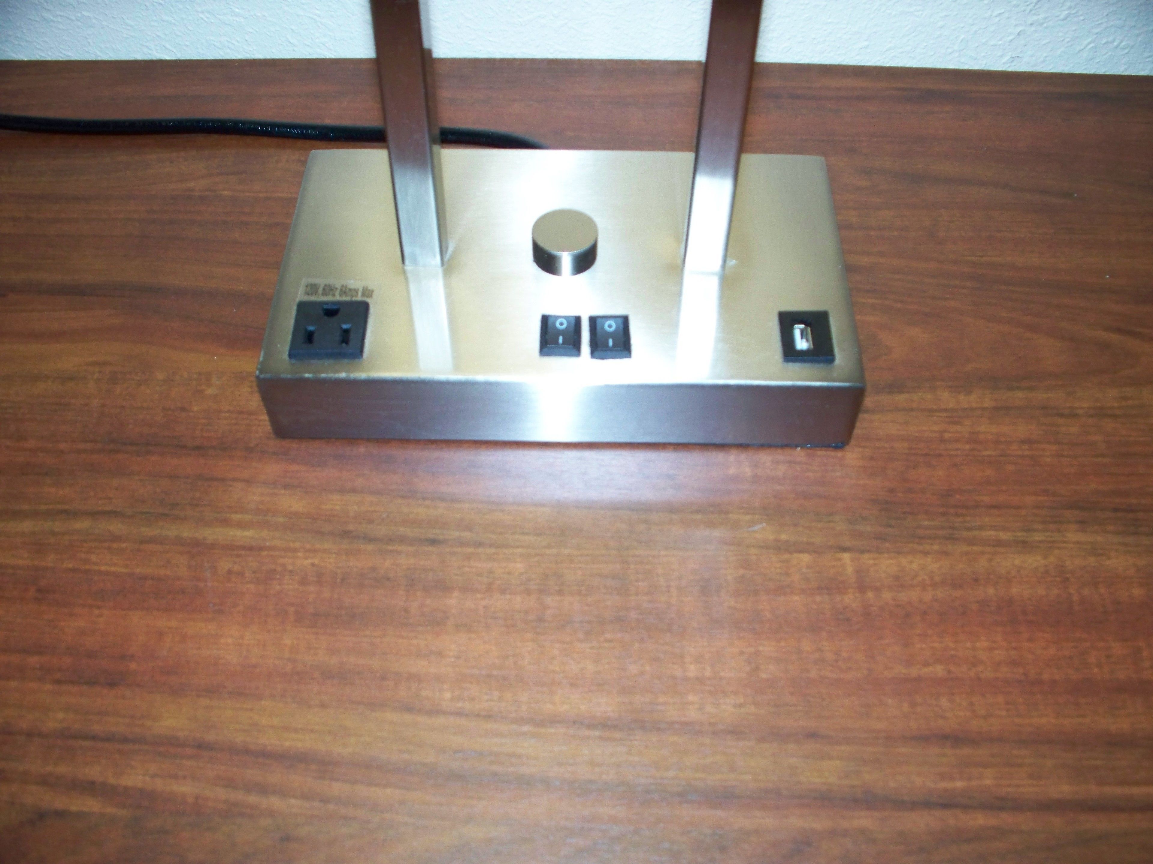 A metallic, rectangular device with two protruding antennas, two USB ports, and a power socket on a wooden surface.