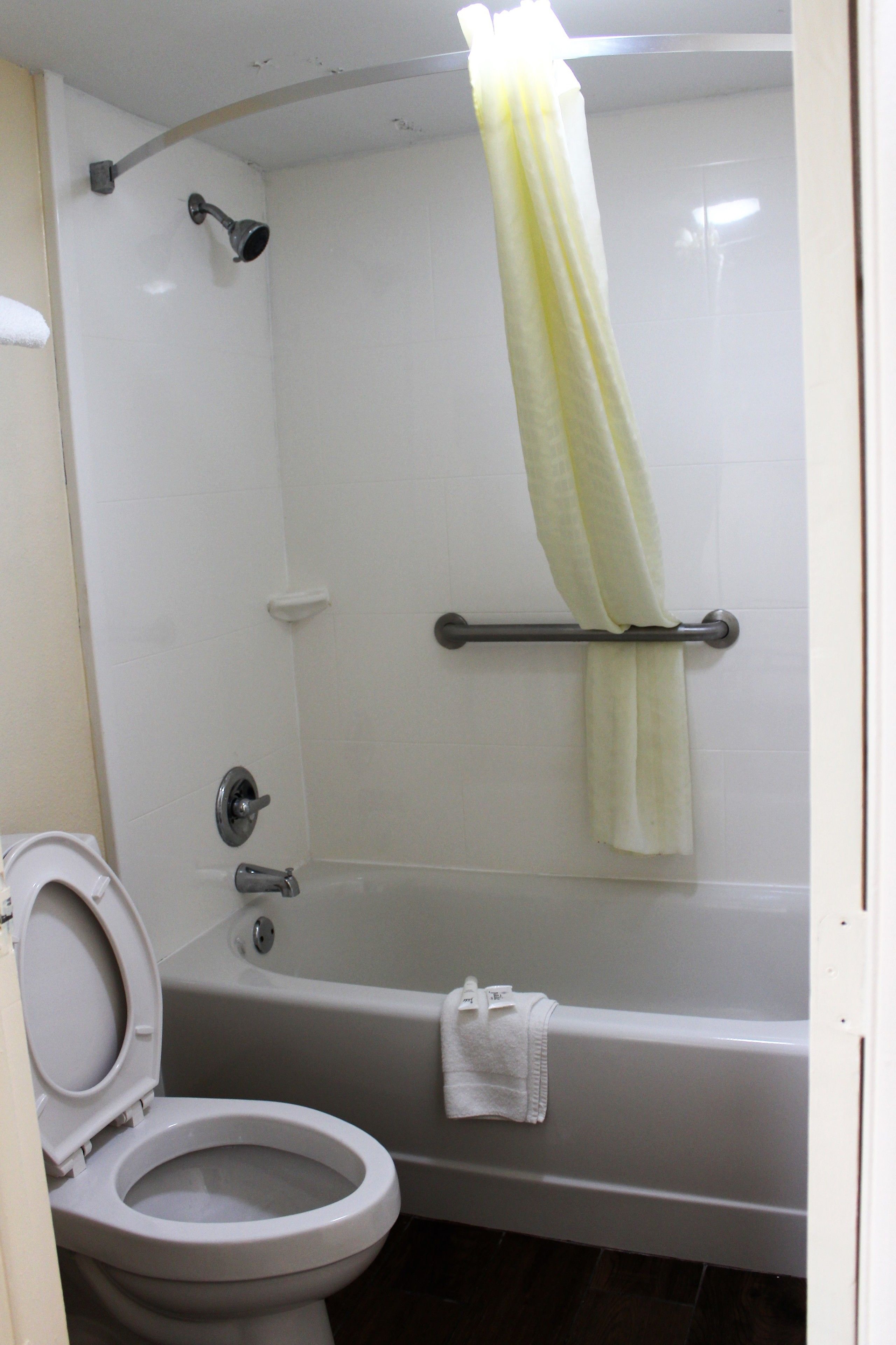 Un baño con inodoro, bañera, ducha y un perchero para toallas.