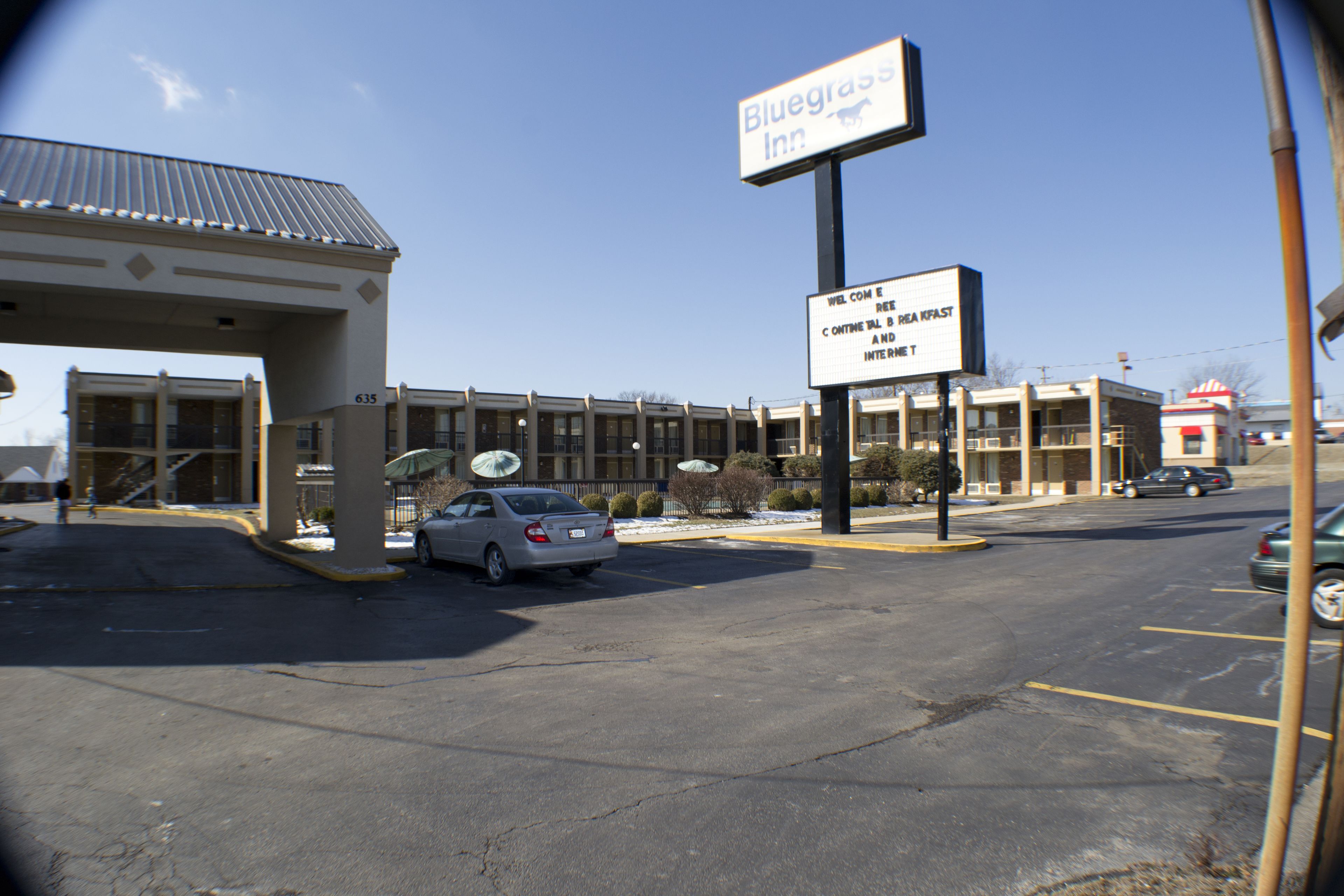 A Bluegrass Inn with a parking lot, a covered entrance, and a building with multiple windows.