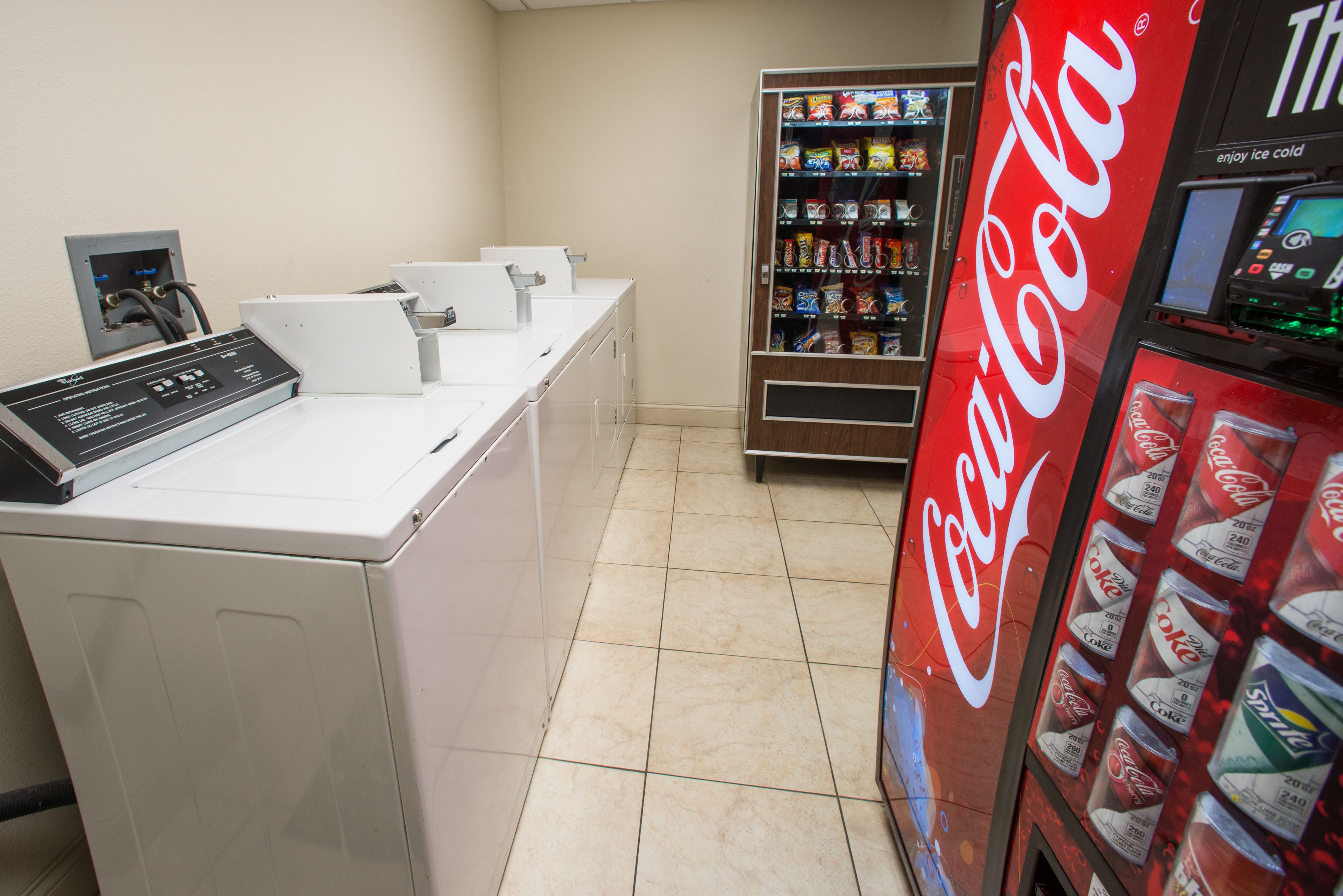 A laundromat with a Coca-Cola vending machine and a washing machine.