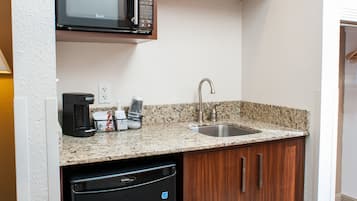 A compact kitchen with a built-in microwave, a sink, and a dishwasher.