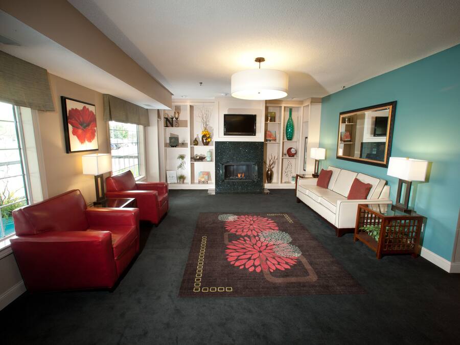 A living room with a fireplace, red and white sofas, a coffee table, and a large mirror.