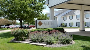 A Northfield Inn sign with a covered parking area and a landscaped garden in front. - Northfield Inn, Suites & Conference Center (Springfield)