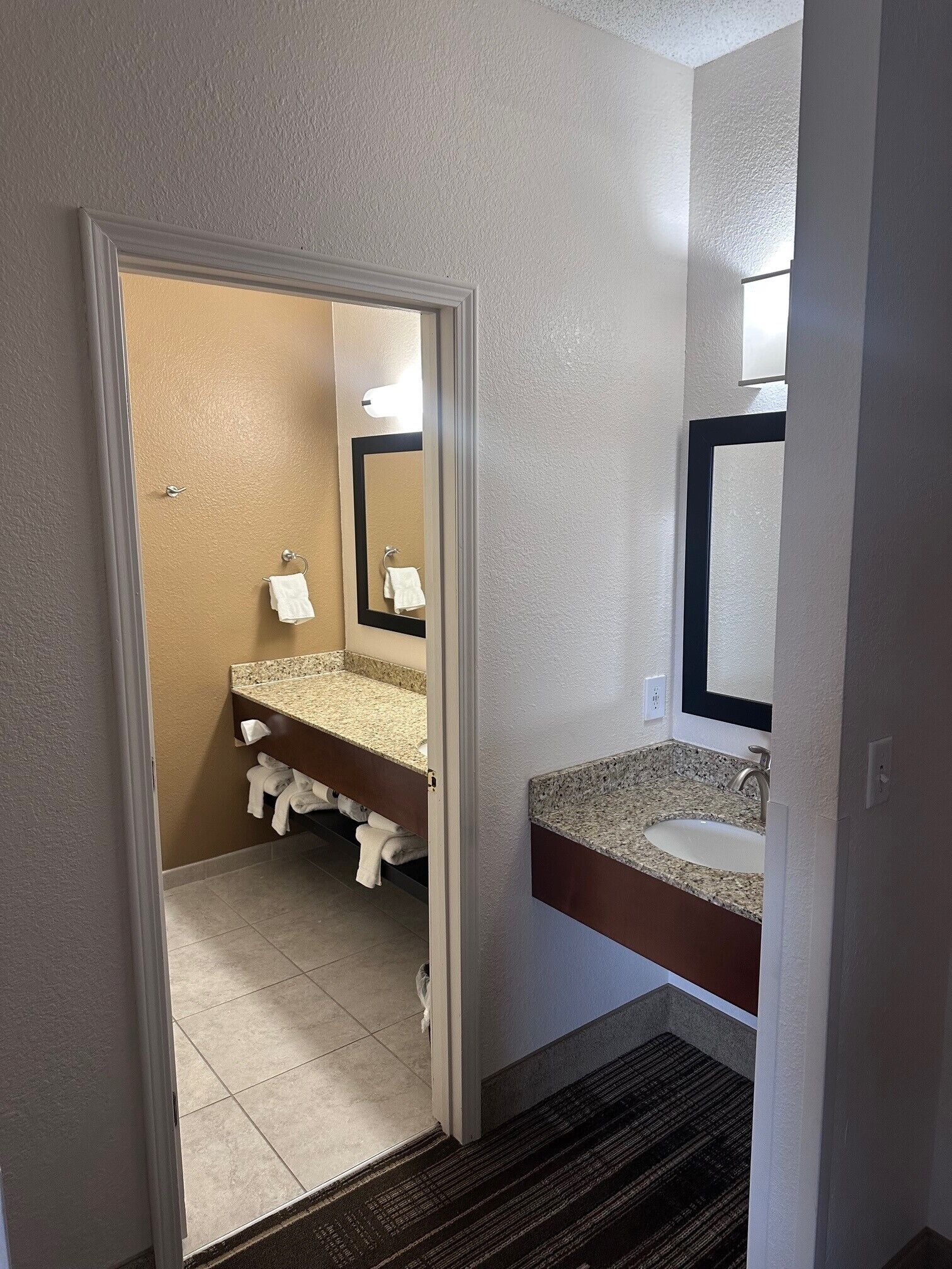 A bathroom with a granite countertop sink, a mirror, and a towel rack.