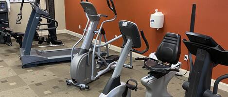 A gym with stationary bikes, treadmills, and a wall-mounted exercise machine.