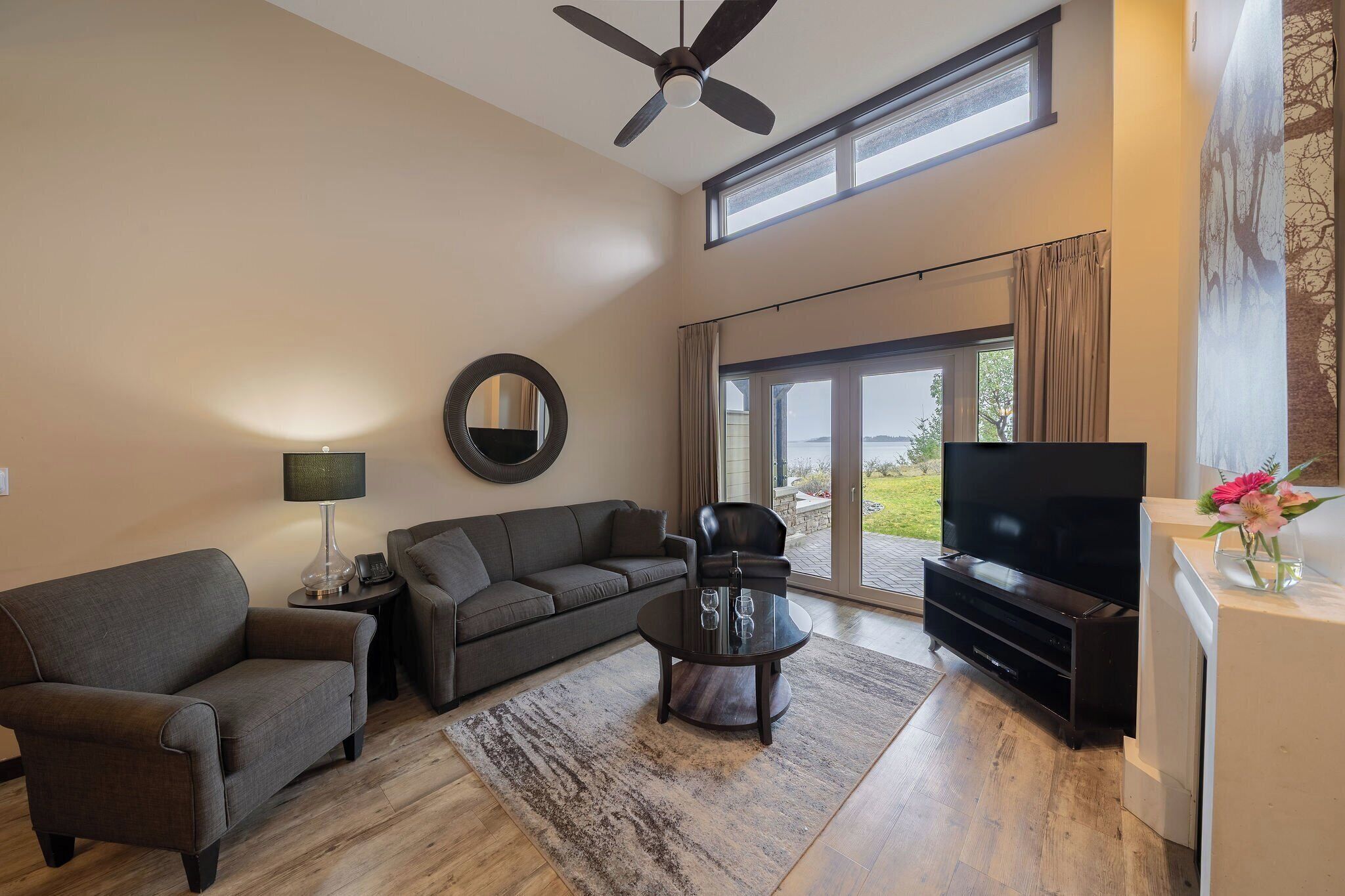 A spacious living room with a sofa, coffee table, TV, and a ceiling fan.