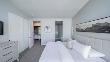 Una habitación de hotel moderna con una cama grande, un aparador, un televisor y un cuadro en la pared.