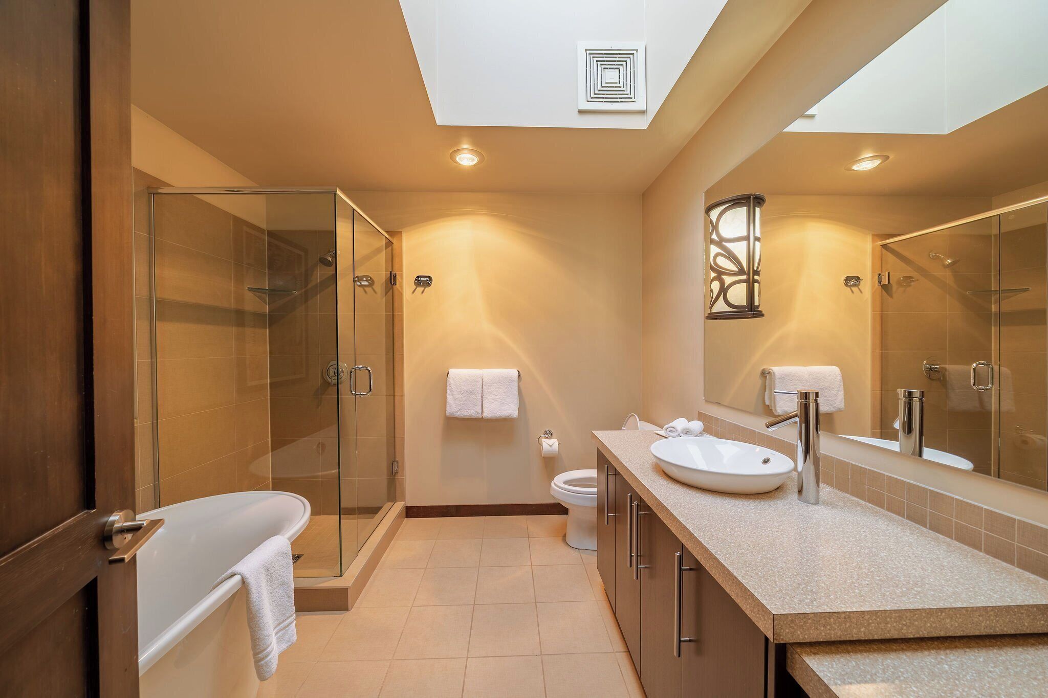 Un baño moderno con cabina de ducha de vidrio, bañera, lavabo e inodoro.