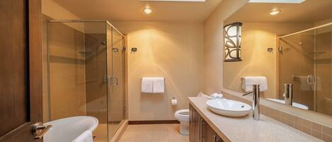 Un baño moderno con cabina de ducha de vidrio, bañera, lavabo e inodoro.