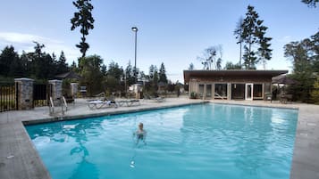 A swimming pool with lounge chairs and a building in the background.
