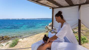 A massage therapy session by a coastal area with a clear view of the sea.