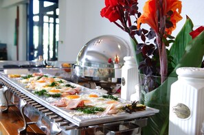 Un montaje tipo bufé con diferentes opciones de comida y un florero decorativo con flores.