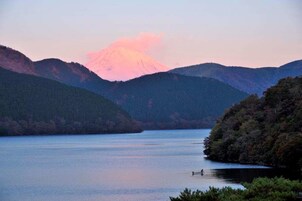Un lago tranquilo rodeado de colinas boscosas con una montaña al fondo.