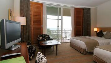 Een hotelkamer met een televisie, een bank, een tafel, een bed en een balkon met uitzicht.