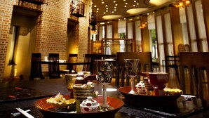 Een restaurantinterieur met bakstenen muren, houten tafels, en diverse gerechten en servies.