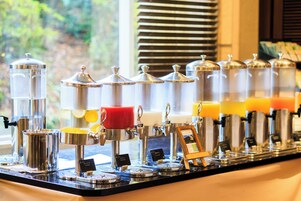 Uma estação de café com vários dispensadores e uma xícara vermelha.