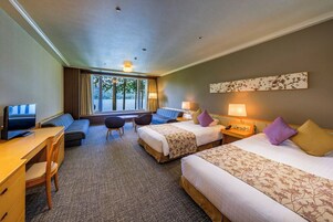 Una habitación de hotel con dos camas, un escritorio, una silla y un televisor.