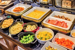 Un bufé con diversos alimentos, como pasta, arroz, verduras y carnes.