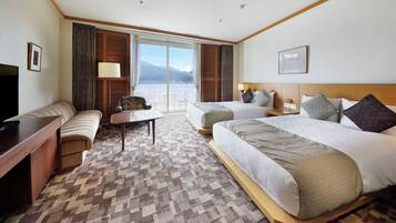 A hotel room with a large bed, a sofa, a desk, and a view of the mountains.