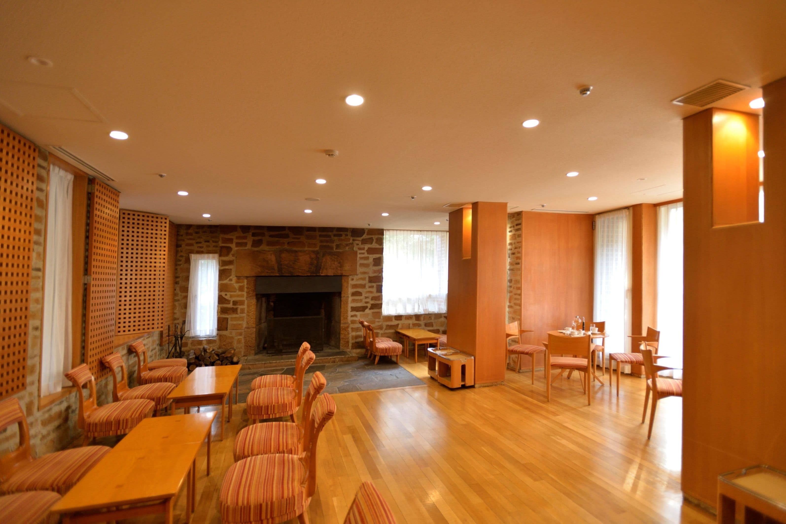 A spacious room with a fireplace, wooden furniture, and a stone wall.