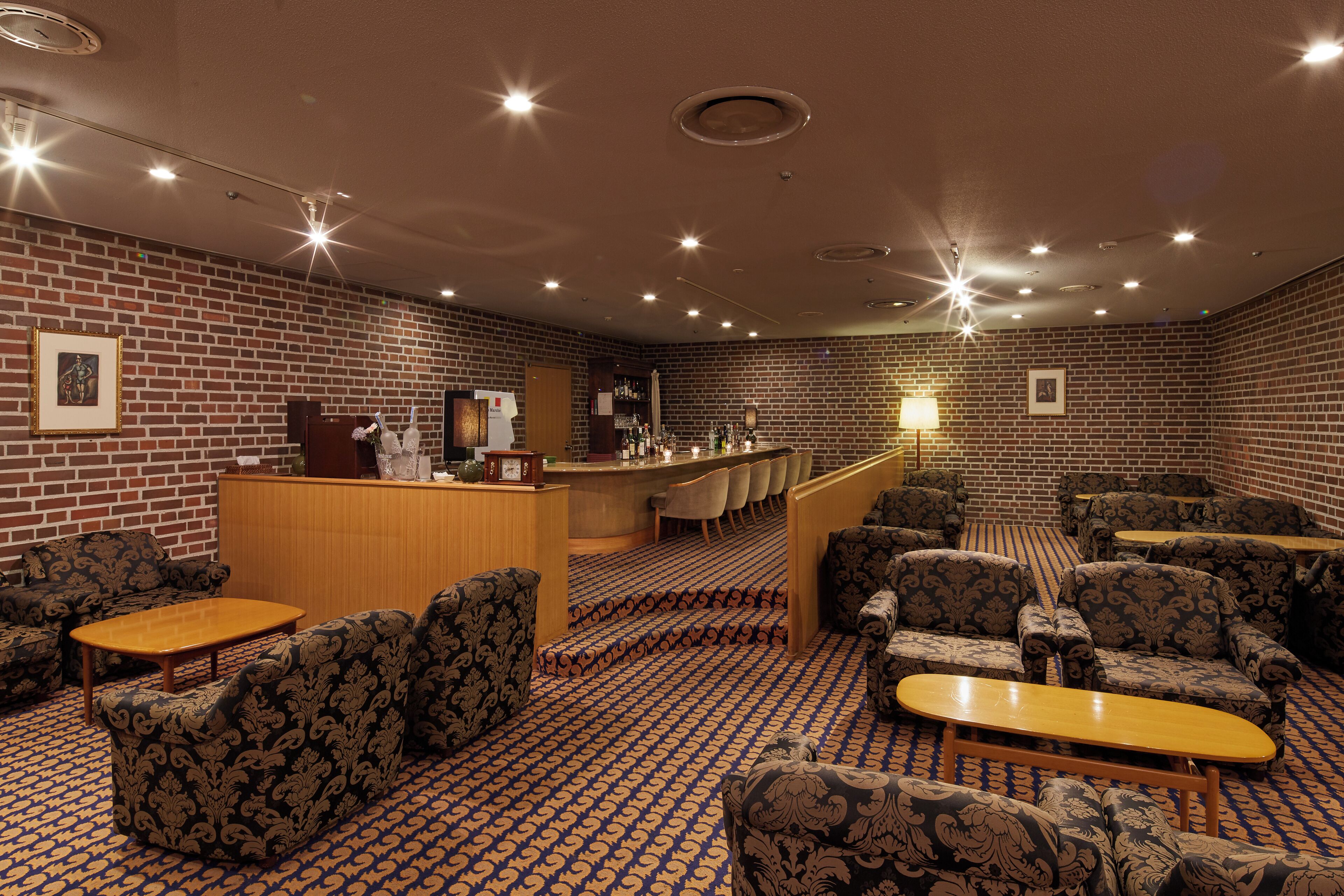 Un hall d'hôtel avec des canapés à motifs, un comptoir d'accueil et un espace bar.