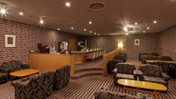 A hotel lobby with patterned sofas, a reception desk, and a bar area.