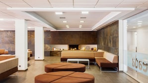 A modern lobby with seating areas, a fireplace, and a glass wall with a number.