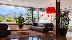 A modern lobby with a sofa, a coffee table, and potted plants.