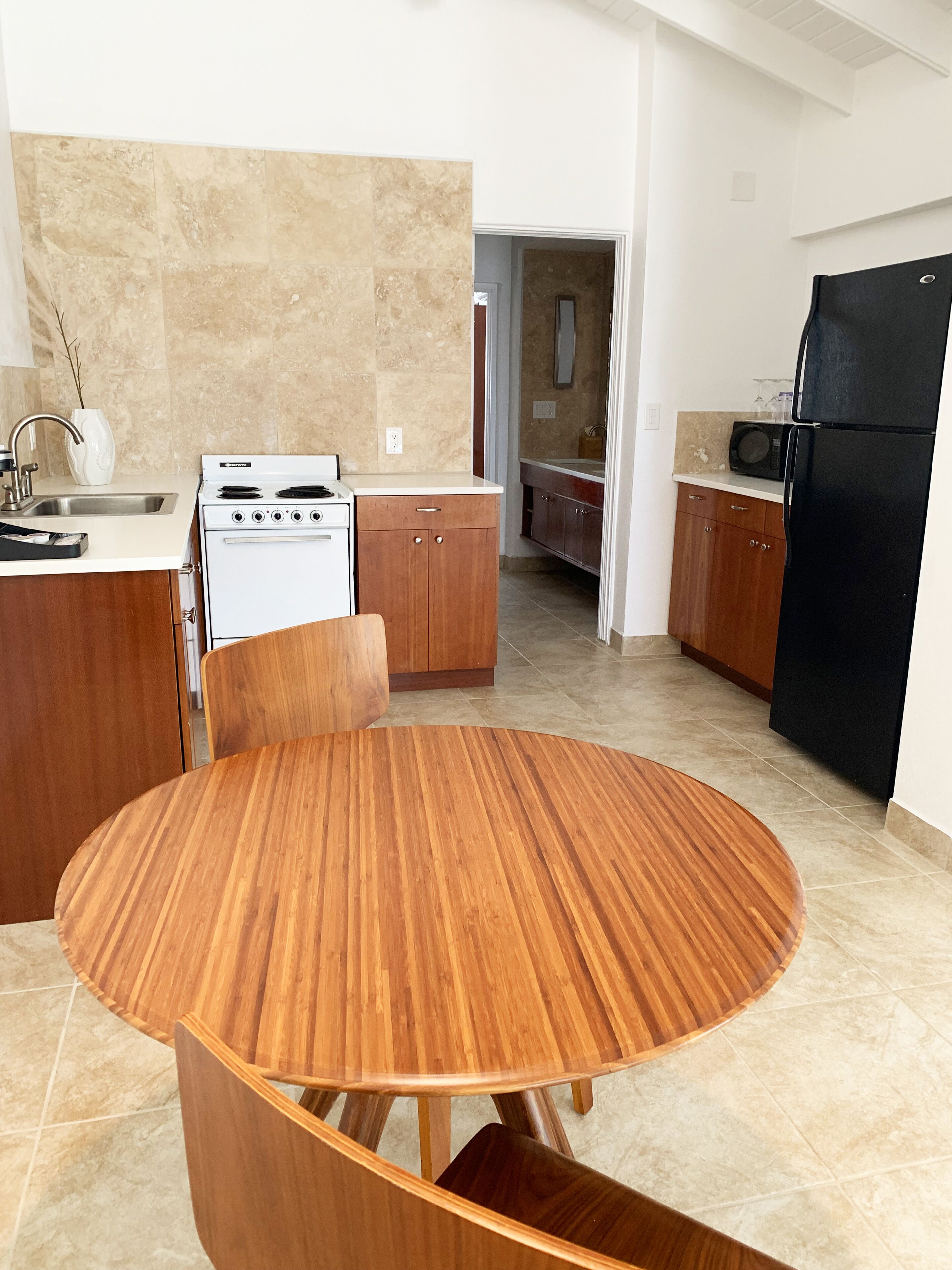 Una cocina moderna con una mesa redonda de madera, una estufa y un refrigerador.
