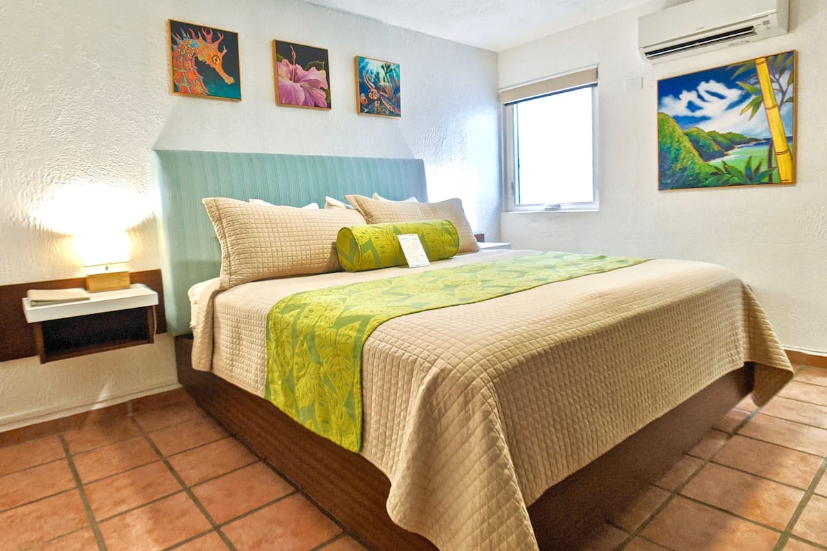 Un dormitorio con cama, mesita de noche, ventana y decoración en la pared.