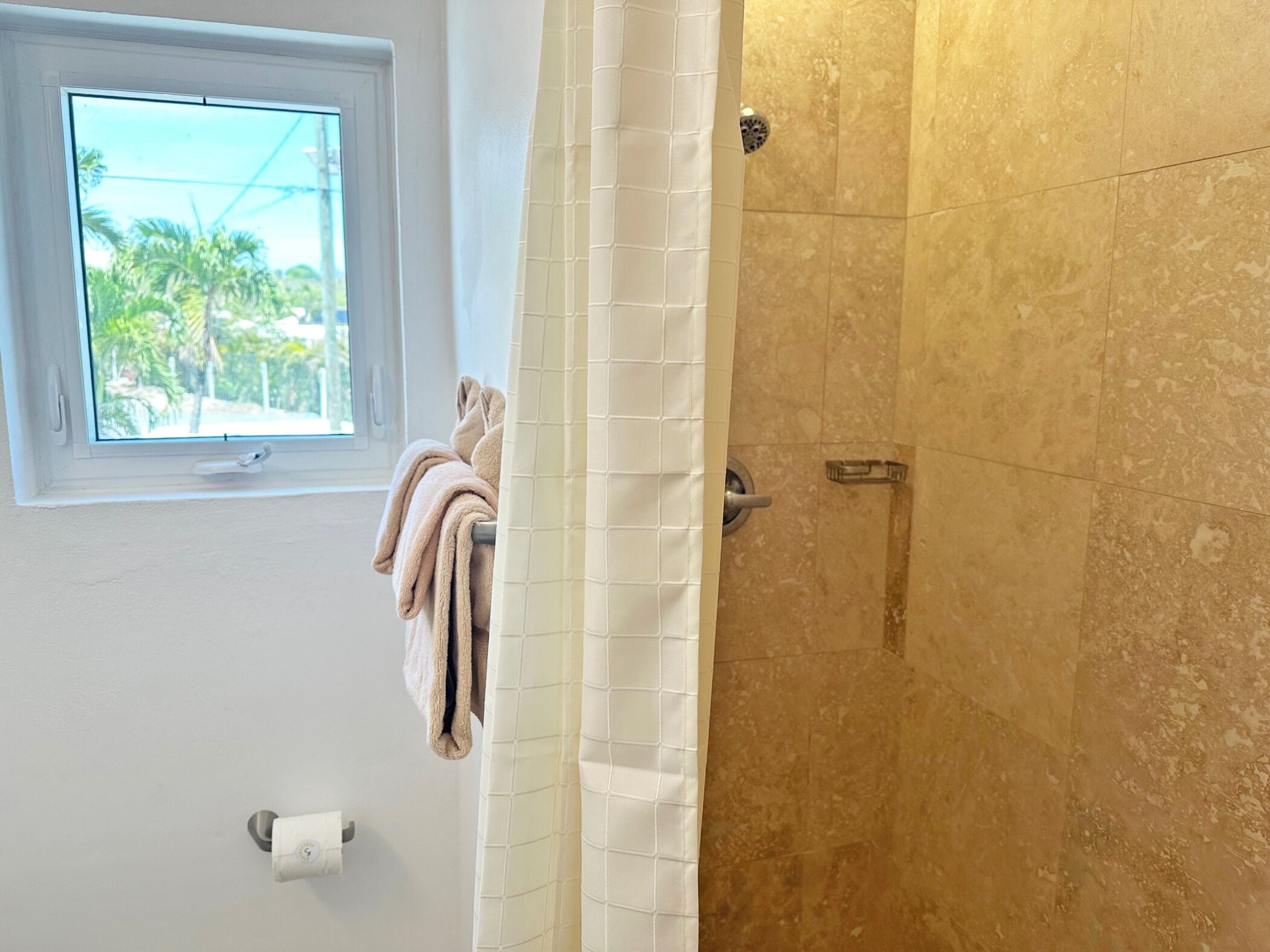 A bathroom with a shower, a window, and a towel rack.