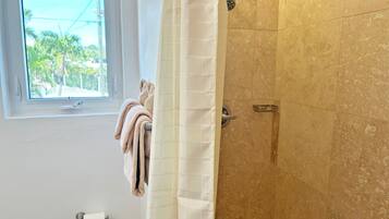 A bathroom with a shower, a window, and a towel rack.