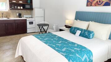 A hotel room with a bed, a small kitchenette, a dining area, and a bathroom.