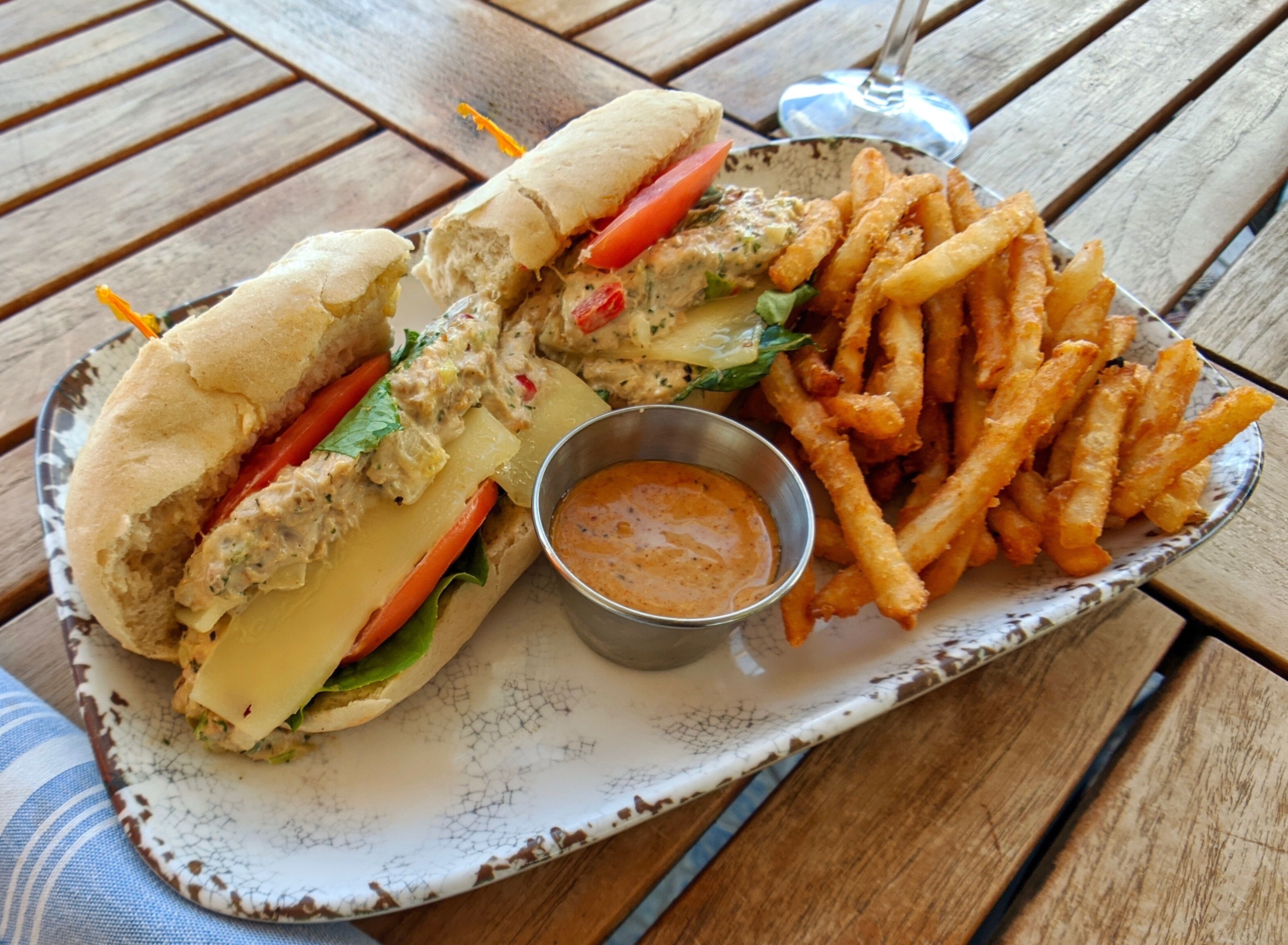 Un sandwich accompagné de frites et d’une sauce pour tremper, le tout servi sur une assiette.