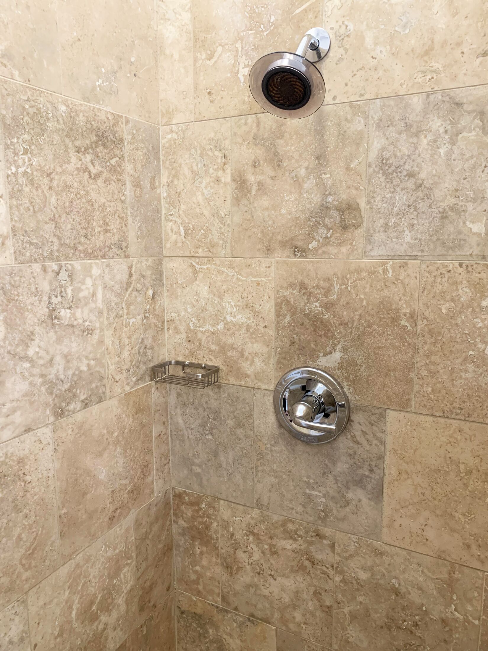 Une douche équipée d’un pommeau de douche à main et d’un robinet fixé au mur.