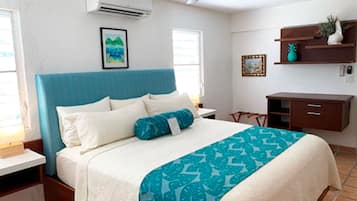 Une chambre à coucher comprenant un lit, un ventilateur de plafond, une table de chevet, un bureau et une étagère avec des objets décoratifs.