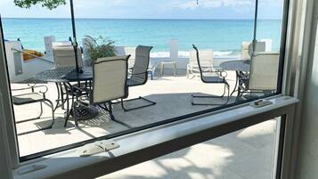 A view from a balcony overlooking a beach with outdoor seating and umbrellas.