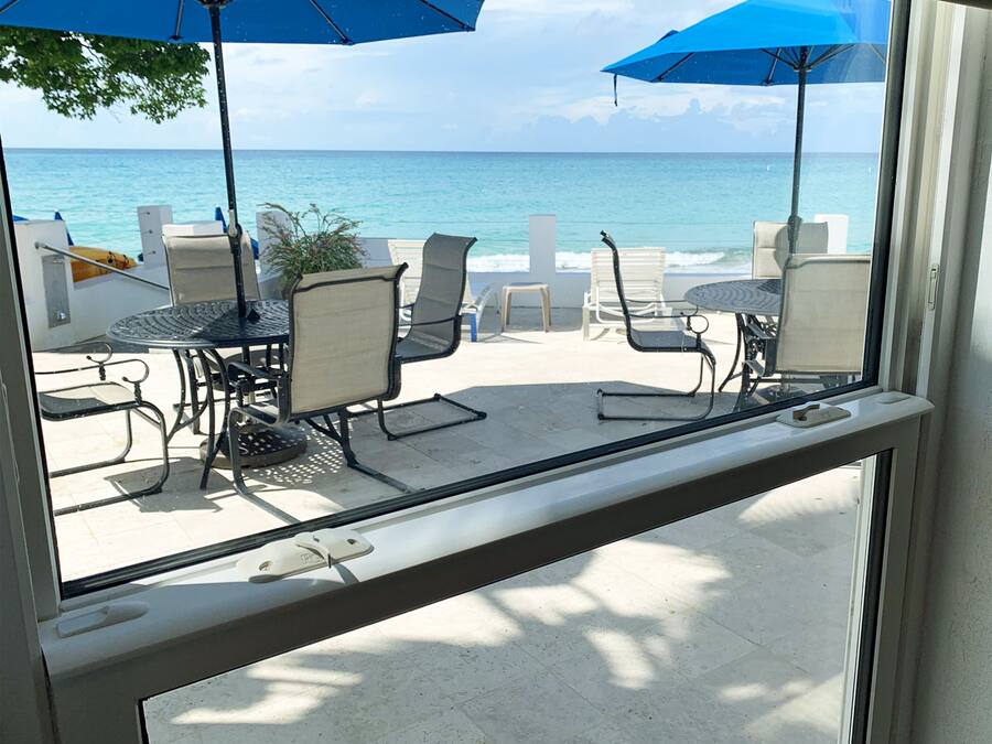 A view from a balcony overlooking a beach with outdoor seating and umbrellas.