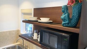 A modern kitchen with a Kenmore microwave, a sink, and a shelf with white bowls and a decorative blue vase.