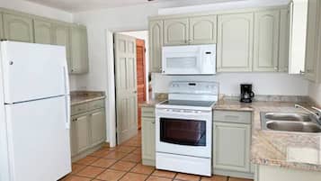 A kitchen with a refrigerator, microwave, stove, and sink.
