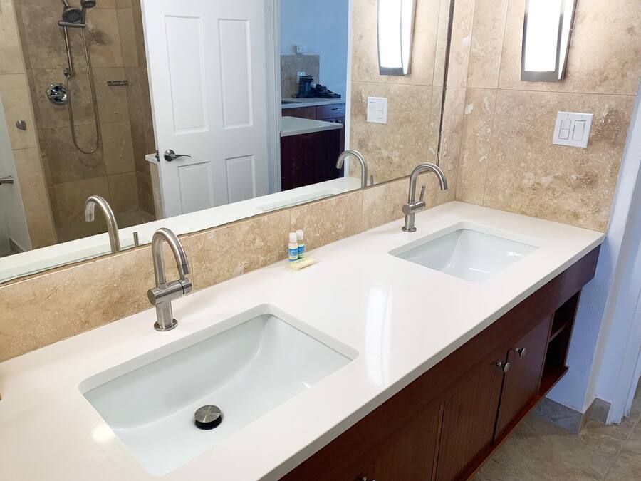 A bathroom with two sinks, a shower, and a mirror.